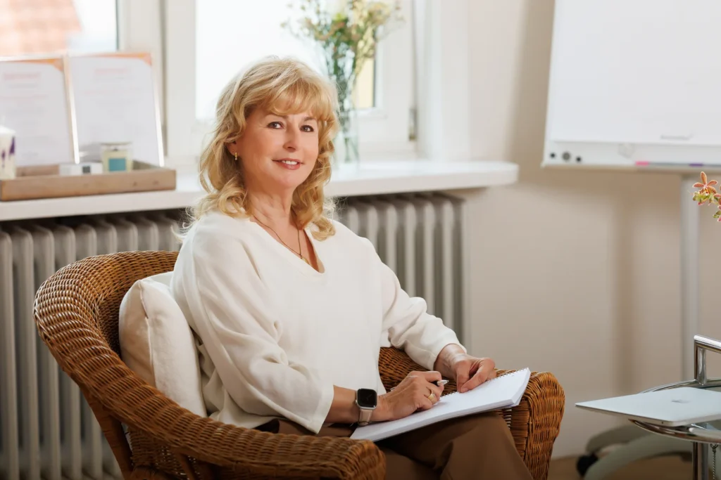 Astrid Justen-Gadesmann sitzt mit einem Notizblock in ihrem Coachingraum.